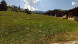 A grassy hillside with buildings in the background. - 100m from shops, 2nd floor, view mountain, balcony, tv, ski locker, 32m², Valmorel (Valmorel)