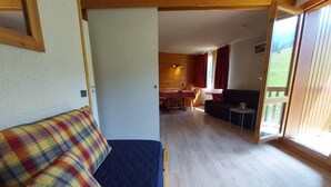 A room with a bed, a sofa, a dining area, and a sliding glass door leading to a balcony. - 100m from shops, 2nd floor, view mountain, balcony, tv, ski locker, 32m², Valmorel (Valmorel)