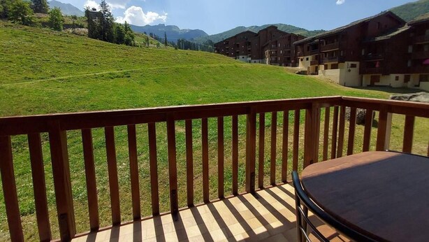 A balcony with a table and chairs, overlooking a grassy hillside and a row of buildings. - 100m from shops, 2nd floor, view mountain, balcony, tv, ski locker, 32m², Valmorel (Valmorel)