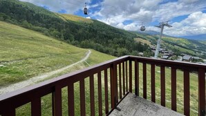 Ein Balkon mit Blick auf eine Berglandschaft, eine Seilbahn und ein kleines Dorf darunter.