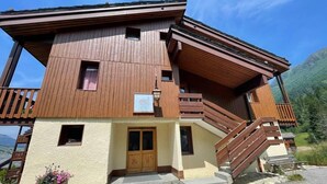 Eine zweistöckige Holzhütte mit Balkon, einer Holztreppe und einer Haustür.