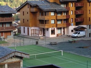A multi-story building with balconies, a tennis court, and a parked van. - 300m from shops, 1st floor, view ski slopes, balcony, tv, ski locker, 13m², Valmorel (Valmorel)