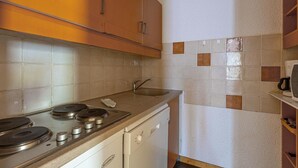 A compact kitchen with a stove, sink, and a coffee maker on the countertop. - 50m from shops, 2nd floor, view mountain, balcony, tv, ski locker, 35m², Valmorel (Valmorel)