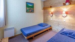 A small, cozy room with a single bed, a heater, and a painting on the wall. - 50m from shops, 2nd floor, view mountain, balcony, tv, ski locker, 35m², Valmorel (Valmorel)