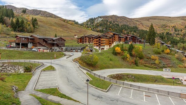 A mountain resort with multiple wooden buildings, a parking area, and a road leading up the hill. - 50m from shops, 2nd floor, view mountain, balcony, tv, ski locker, 35m², Valmorel (Valmorel)