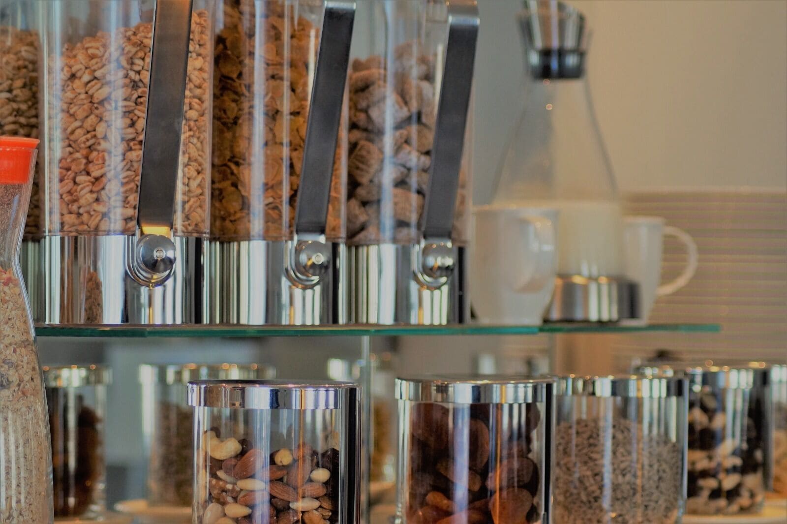 A coffee shop with multiple glass containers filled with various coffee beans and nuts, arranged on shelves.