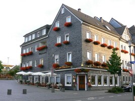 Hotel de vários andares com fachada de pedra, várias janelas e caixas com flores na fachada.