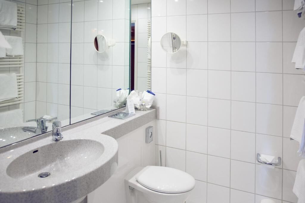 Un baño moderno con lavamanos, inodoro y un espejo grande.