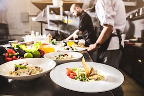 Un chef preparando comida en una cocina, con varios platos e ingredientes sobre la encimera.