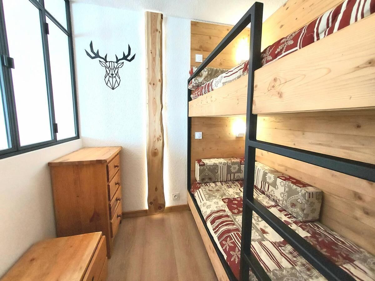 Une chambre avec un lit superposé, une commode en bois et une décoration murale représentant une tête de cerf.
