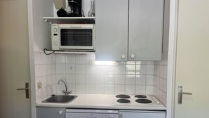 A compact kitchen with a sink, stove, and microwave.
