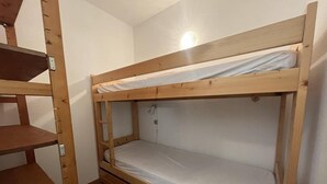 A bunk bed with a wooden frame and a white mattress.