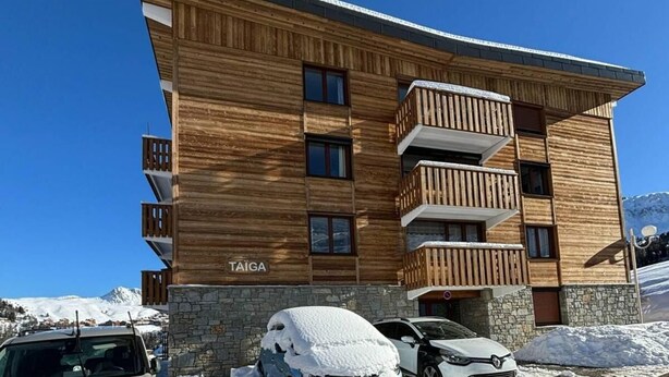 A multi-story wooden building with balconies, labeled "TAIGA," in a snowy environment.