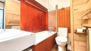 A modern bathroom with a wooden interior, a white sink, and a toilet.