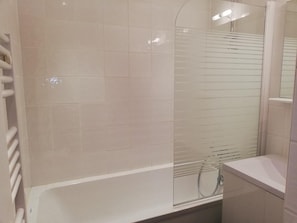 A bathroom with a bathtub, a glass shower enclosure, and a white tiled wall. - 1st floor, view resort, terrace, tv, 36m², La Plagne (La Plagne)