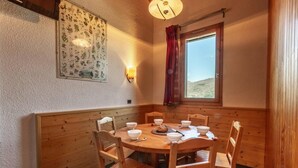 Zona pranzo con un tavolo rotondo in legno, sei sedie e un lampadario a parete.