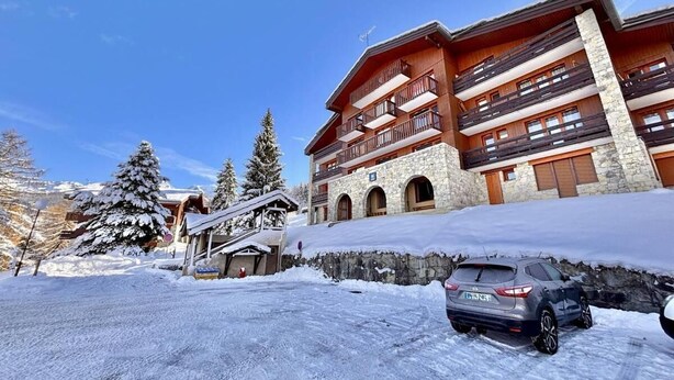 A multi-story hotel with stone facade and balconies, surrounded by snow-covered trees. - 300m from resort center, view mountain, terrace, tv, ski locker, 20m², Montchavin La Plagne (Bellentre)