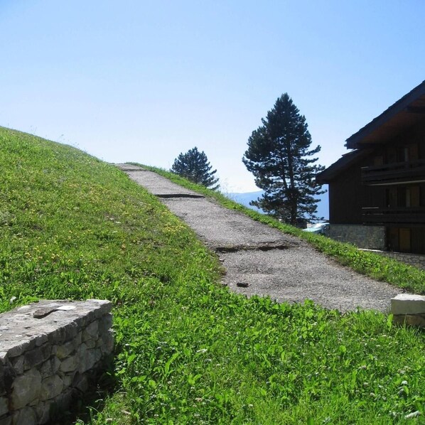 A stone pathway leading to a wooden building with a view of a mountain.
