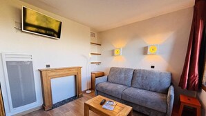 A living room with a sofa, a wooden coffee table, a fireplace, and a television mounted on the wall. - 50m from ski slopes, 2nd floor, view mountain, balcony, tv, ski locker, 27m², Montchavin La Plagne (Bellentre)