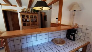 A kitchen with a wooden countertop, tiled backsplash, a coffee maker, and a hanging lamp. - Balcony, tv, 65m², Méribel-Mottaret (Méribel - Les Allues)
