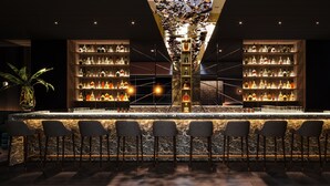 A bar area with a marble countertop, multiple shelves of liquor bottles, and bar stools. - AMANO Covent Garden (London)