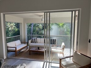 Een balkon met een bank, stoelen en een bijzettafeltje.
