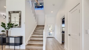Ein modernes Interieur mit einer Treppe, einem schwarzen Konsolentisch mit Pflanze und einem großen Spiegel an der Wand.
