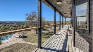 Eine Holzterrasse mit Pool und Liegestühlen, mit Blick auf eine malerische Landschaft.