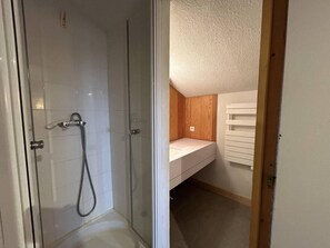 A bathroom with a glass shower enclosure, a white sink with a wooden vanity, and a white ceiling. - 20m from ski slopes, 4th floor, view building, 13m², Méribel-Mottaret (Méribel - Les Allues)