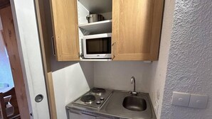 Eine kleine Küchenzeile mit Mikrowelle, Herd und Spüle.