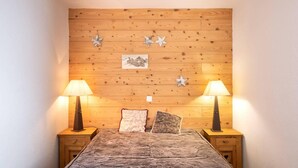 A bedroom with a wooden headboard, two bedside lamps, a bed with a textured blanket, and decorative star-shaped wall hangings.