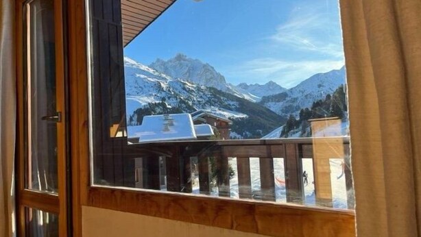 A balcony with a view of snow-covered mountains and a clear sky.