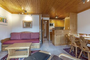 Un interior acogedor con techo de madera, un sofá, una mesa de comedor y una zona de cocina.