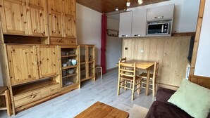 A wooden interior with a dining table and chairs, a sofa, and built-in wooden cabinets. - 180m from shops, floor -1, view mountain, balcony, 29m², Méribel-Mottaret (Méribel - Les Allues)