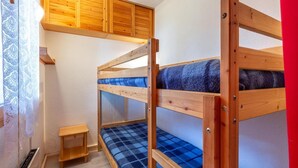 A bunk bed room with wooden frames, a small wooden stool, and a window with lace curtains. - 180m from shops, floor -1, view mountain, balcony, 29m², Méribel-Mottaret (Méribel - Les Allues)