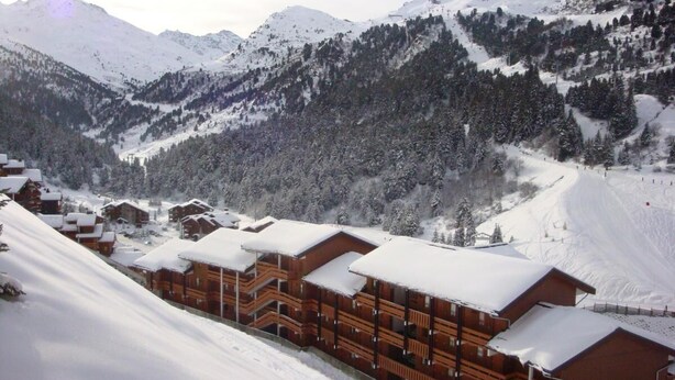 A snow-covered lodge with multiple wooden cabins, a ski slope in the background, and a mountainous landscape. - 180m from shops, floor -1, view mountain, balcony, 29m², Méribel-Mottaret (Méribel - Les Allues)