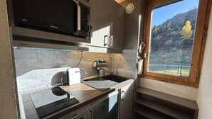 A compact kitchen with a microwave, sink, and dishwasher. There's a window with a view of a lake and trees.
