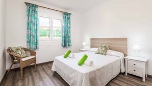 Una habitación de hotel con cama, una silla, una mesita de noche y una ventana con cortinas.