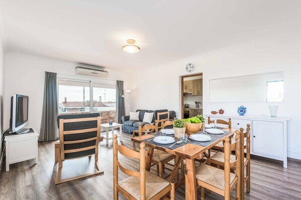 A modern living room with a dining area, a sofa set, and a kitchen area with cabinets and a countertop. - Villa Paula Punta Prima (Punta Prima)