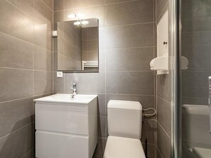 A modern bathroom with a white sink, toilet, and shower. - Resort center, 1st floor, view valley, balcony, ski locker, 16m², Méribel-Mottaret (Méribel - Les Allues)
