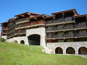 Um hotel de vários andares com fachada em pedra e madeira, varandas e janelas em arco.