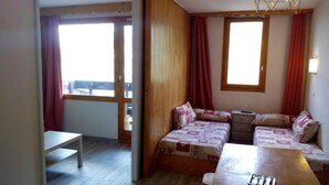A room with two beds, a wooden table, and a bench. - 50m from ski slopes, 2nd floor, balcony, tv, 28m², Méribel-Mottaret (Méribel - Les Allues)
