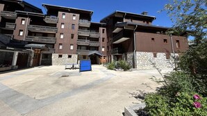 A multi-story building with balconies and a stone facade. - 50m from ski slopes, 2nd floor, balcony, tv, 28m², Méribel-Mottaret (Méribel - Les Allues)