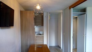 A modern kitchen with a wooden countertop and a built-in oven. There is a dining table with two stools in the foreground. - 50m from ski slopes, 2nd floor, balcony, tv, 28m², Méribel-Mottaret (Méribel - Les Allues)