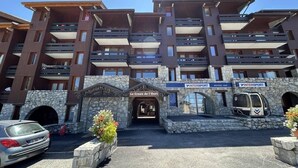 En hotelbygning med flere etager, en stenfassade, balkoner og et skilt med 'Le Creux de l'Ours'.