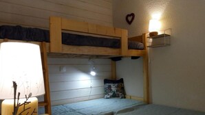 Et soveværelse med køjeseng, en sengebordlampe, en hjerteformet pynteting og en hyld på væggen.