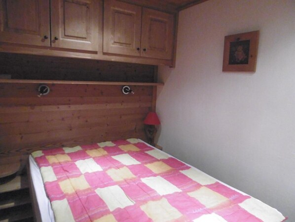 A room with a bed, wooden cabinets, and a wall-mounted picture.