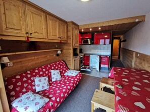 A compact living space with a sofa, a small table, and a kitchenette area.