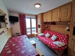 A room with a bed, a sofa, a table, and a TV. - 10m from ski slopes, 1st floor, view ski slopes, balcony, 32m², Méribel-Mottaret (Méribel - Les Allues)