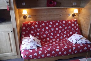 A cozy room with a wooden bunk bed and a red sofa bed with heart patterns. - 10m from ski slopes, 1st floor, view ski slopes, balcony, 32m², Méribel-Mottaret (Méribel - Les Allues)